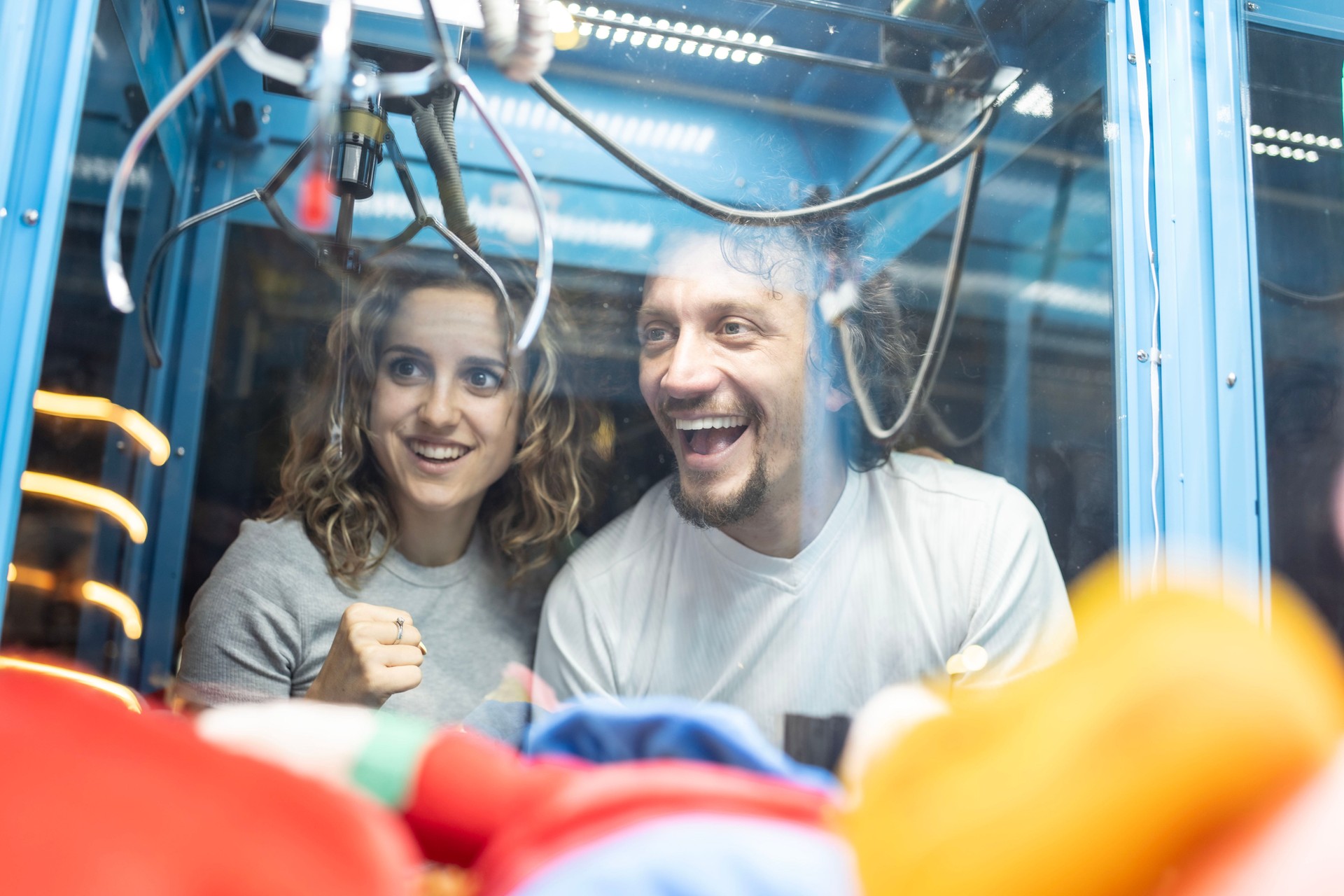 Happy Couple Enjoying a Claw Machine Game at an Arcade